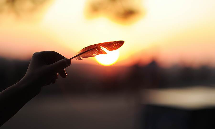 Holding a feather at sunset